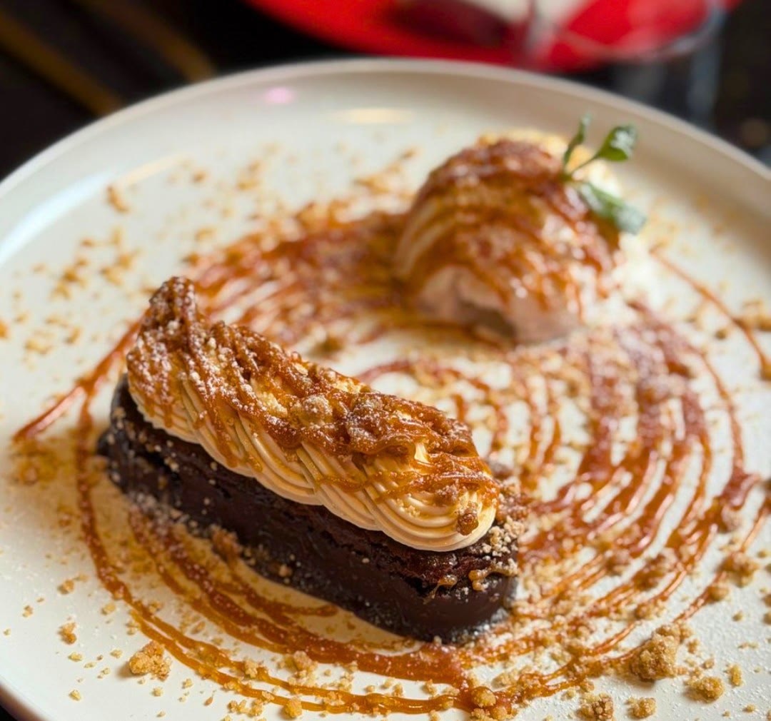 Dolce al cioccolato con crema, caramello e crumble, servito con una pallina di gelato