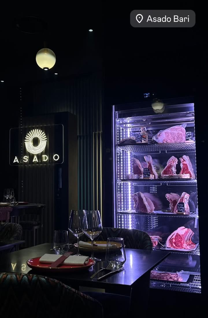 La cella di frollatura in sala, con i tagli esposti e l'insegna di Asado