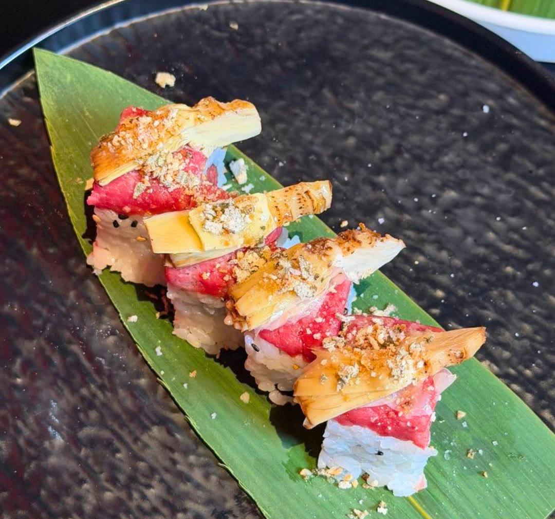 Quattro pezzi di sushi di carne con carciofo grigliato, su una foglia di bambù